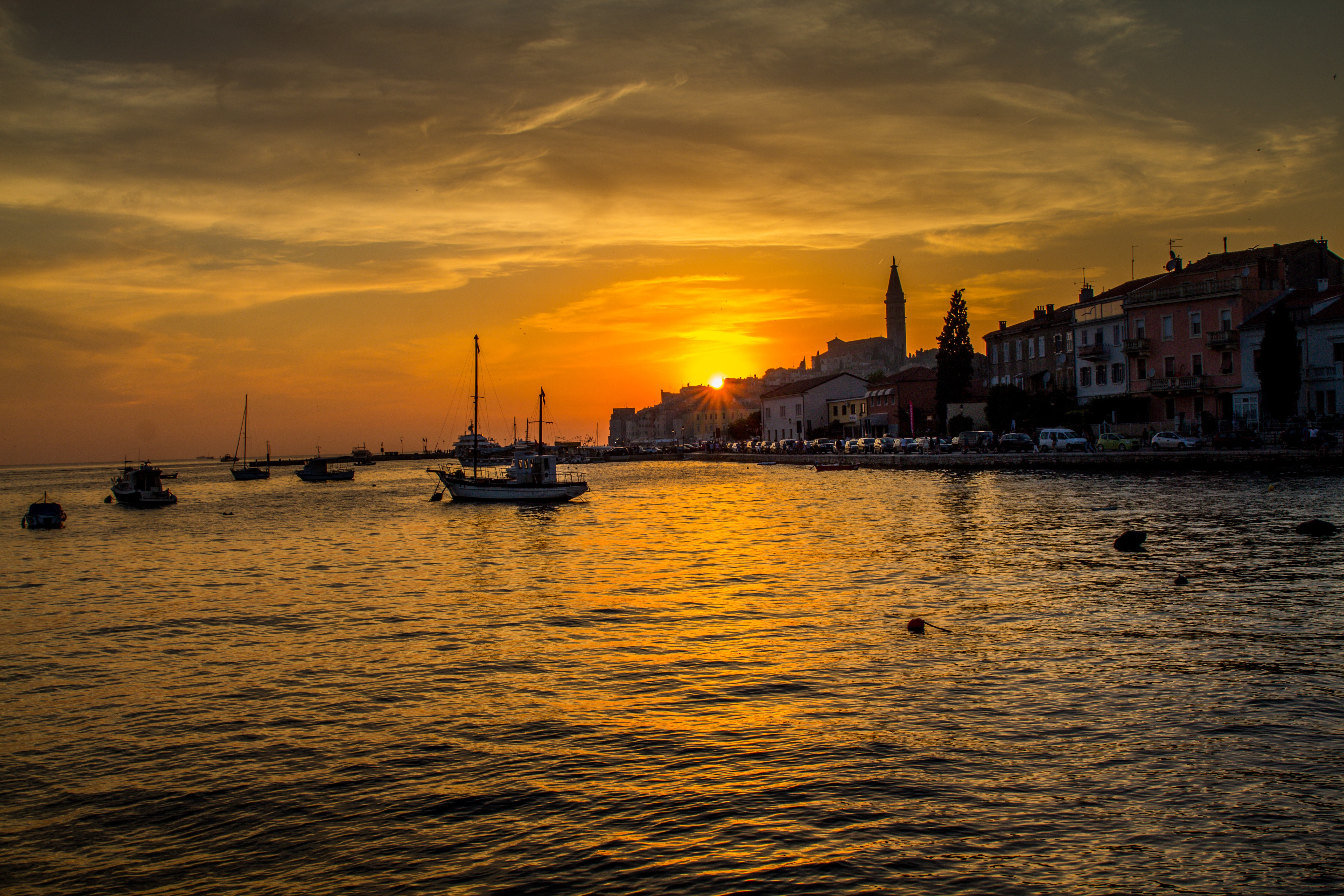 Romantic sunset in Rovinj Croatia with boats on the sea, golden sky, and historic old town skyline.
