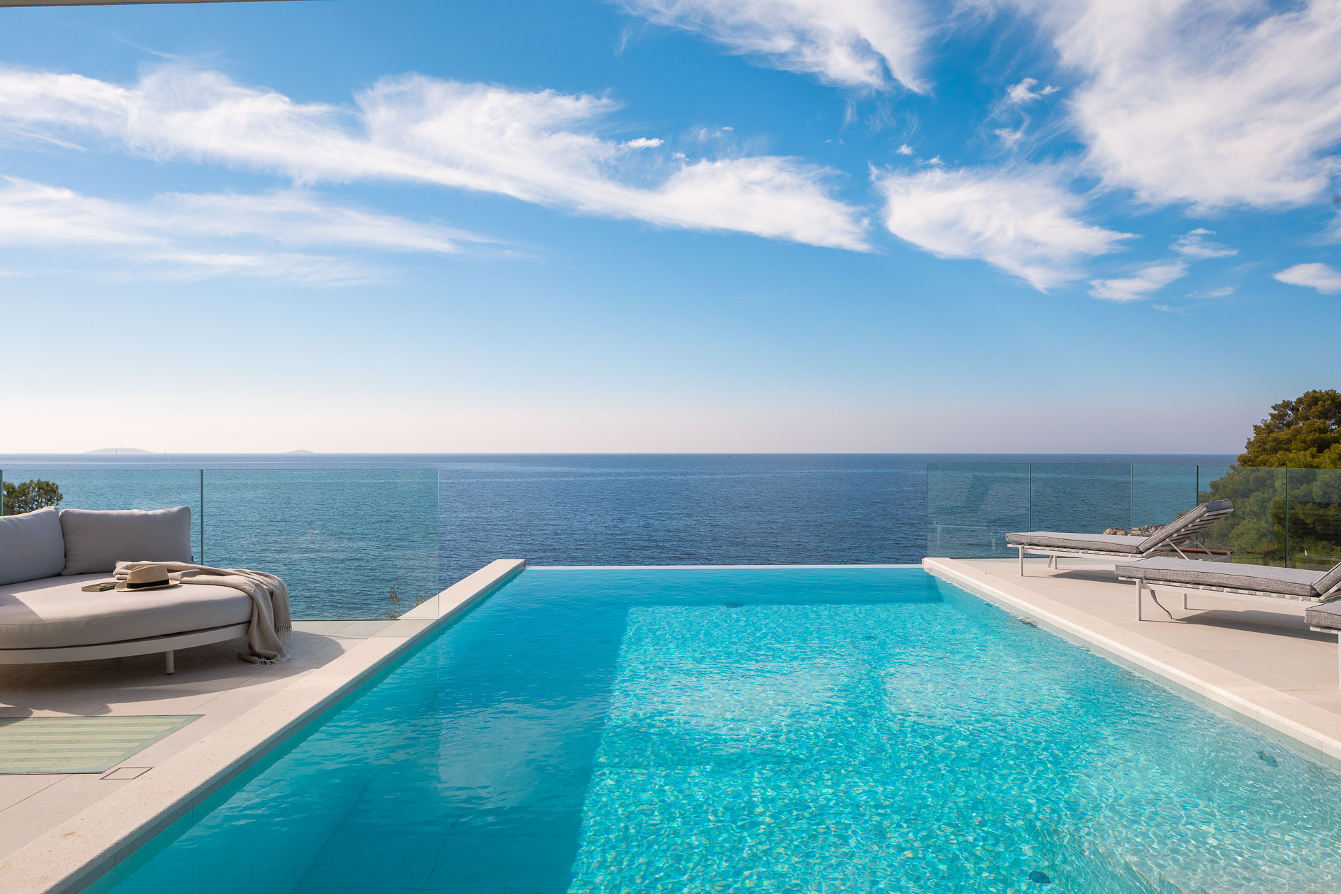 Infinity-Pool der Villa Dream Pearl mit Blick auf das kristallklare Meer, Sonnenliegen und einer entspannenden Terrasse unter blauem Himmel