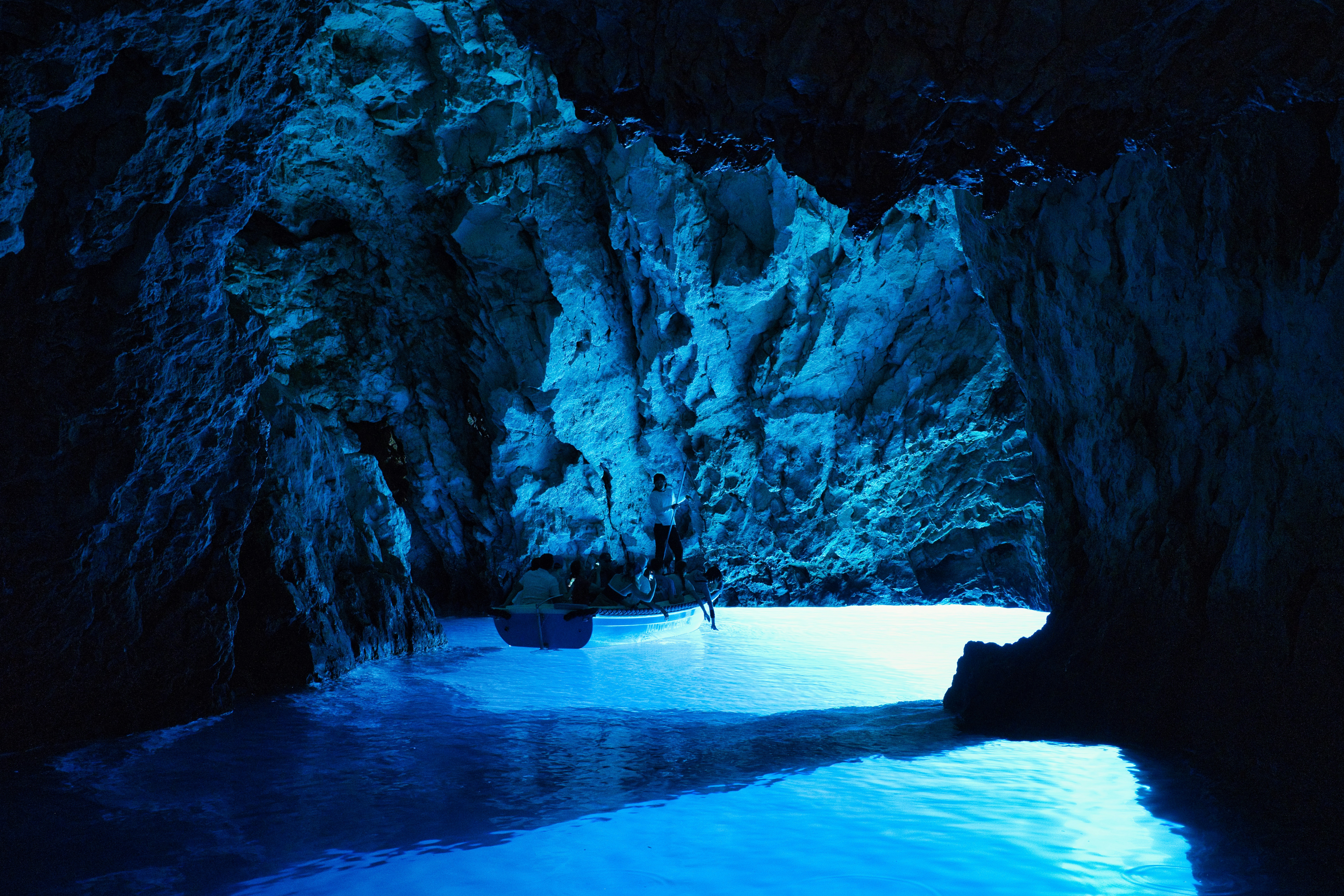 Blue Cave on Biševo Island near Vis, illuminated by vivid blue light, with visitors exploring the sea cave by boat.