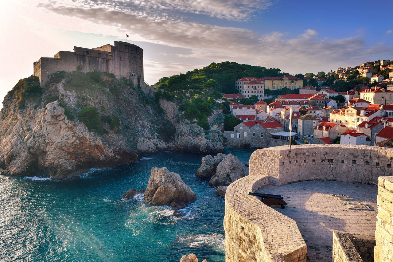 Spektakuläre Aussicht auf die Festung Lovrijenac in Dubrovnik und die steinernen Altstadtmauern über dem kristallklaren Adriatischen Meer unter blauem Himmel.
