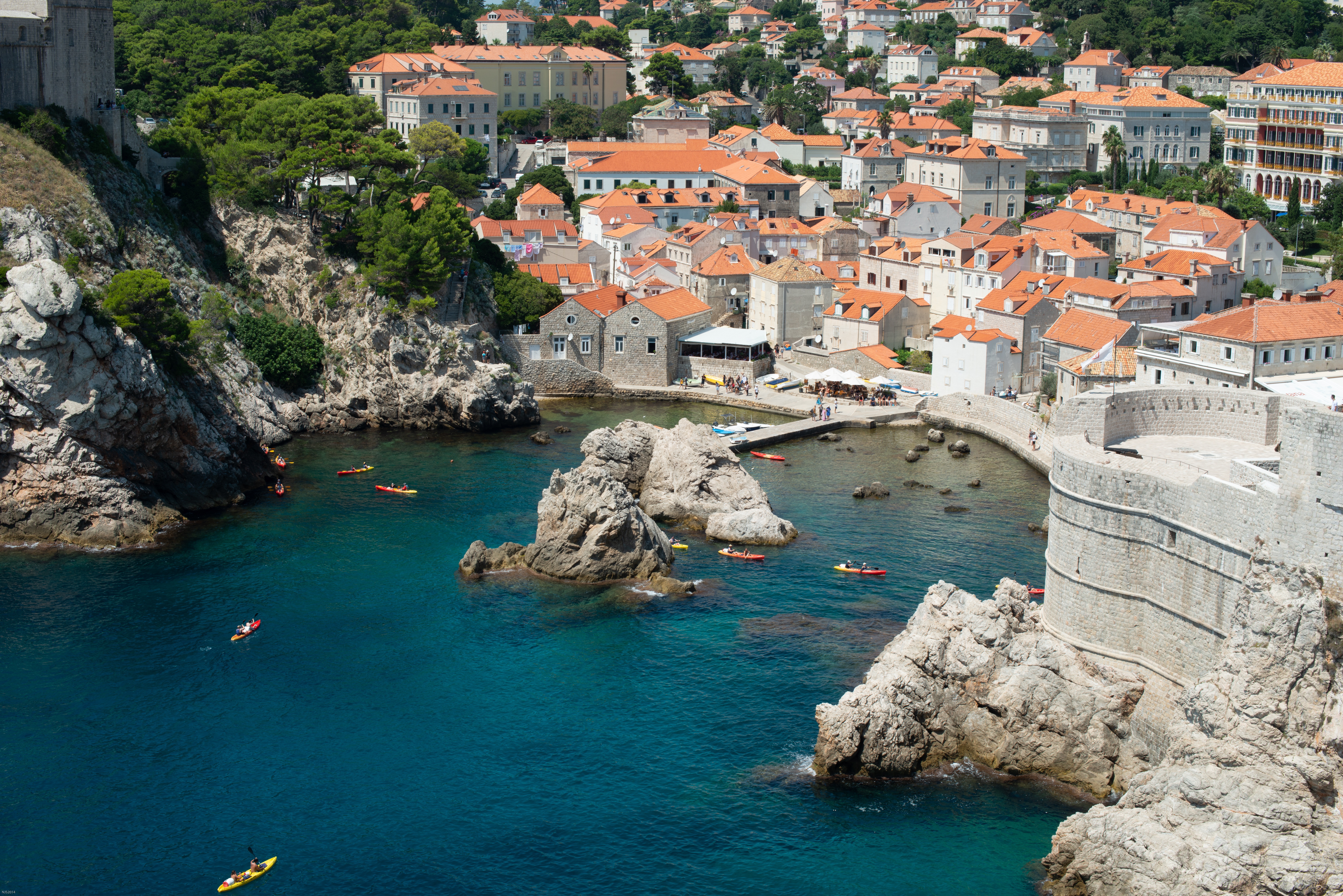 Dubrovnik City Walls overlooking the Adriatic Sea with historic Old Town, rocky coastline, and sea kayaks