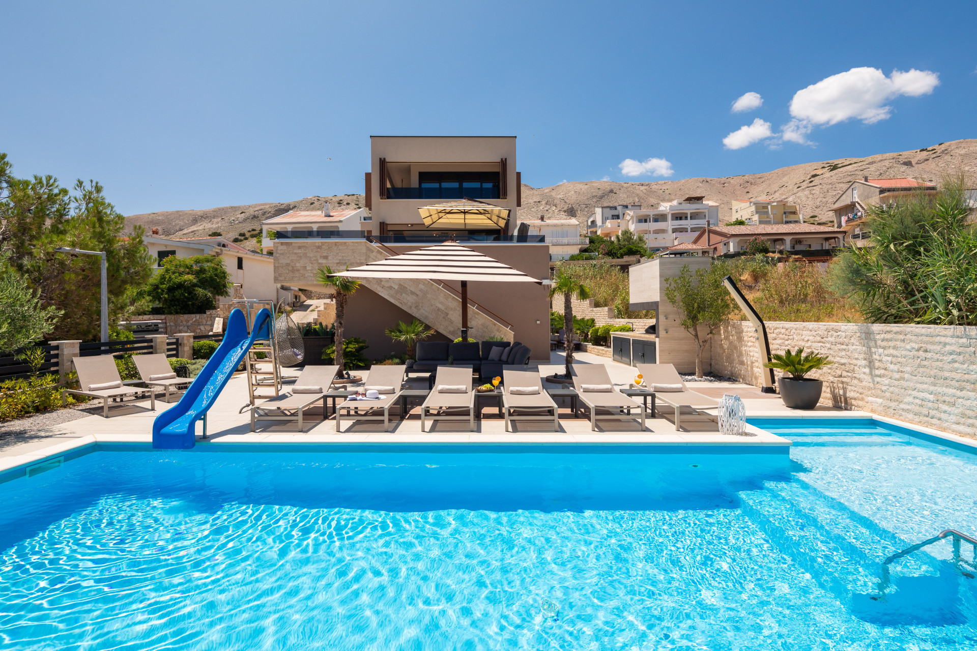 Moderne luksusvilla Villa Emma med en rummelig privat swimmingpool med vandrutsjebane, omgivet af en solterrasse med liggestole og skyggefulde siddeområder