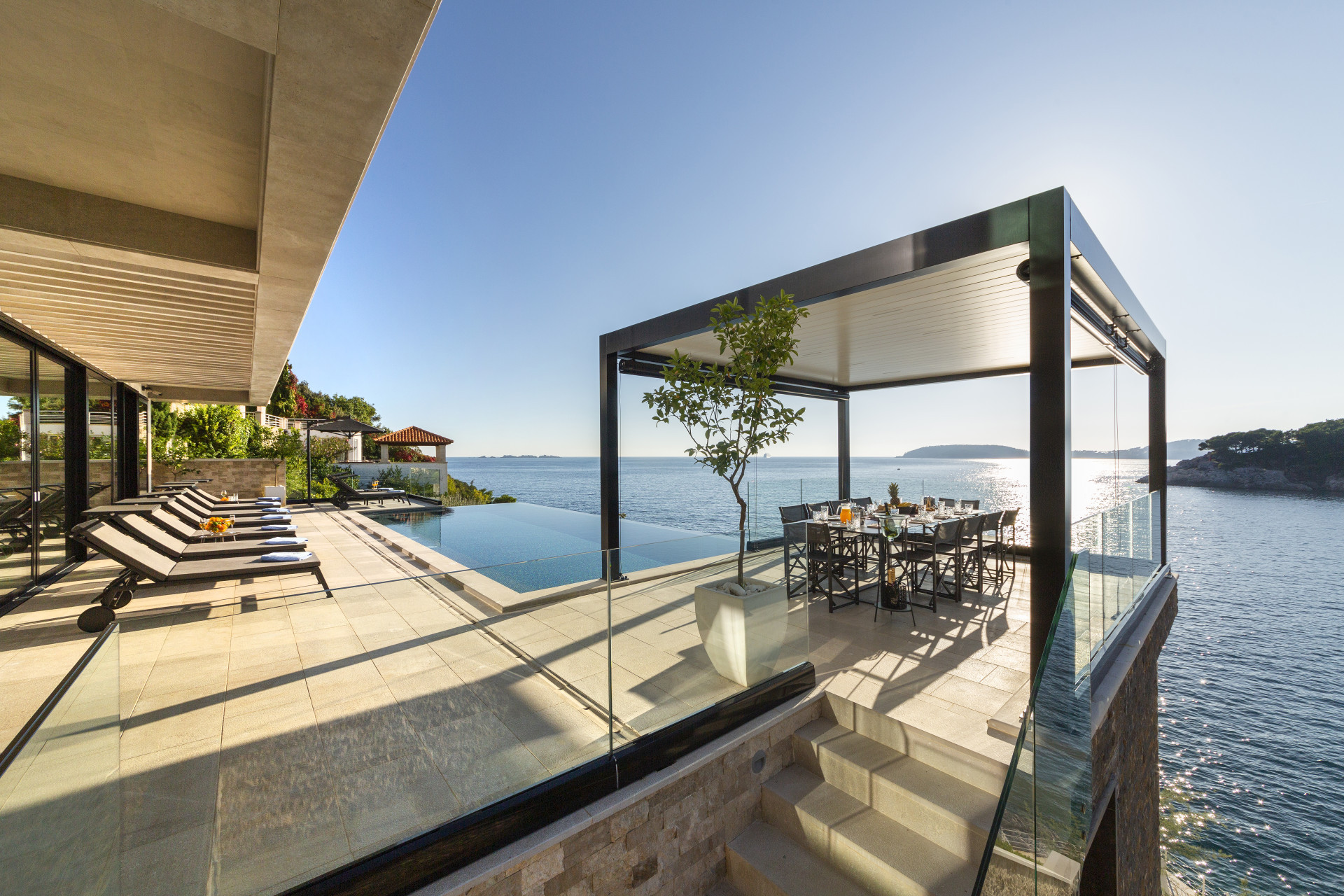 Luxury terrace at Villa Amelie featuring an infinity pool, sun loungers, and a covered outdoor dining area overlooking the Adriatic Sea.