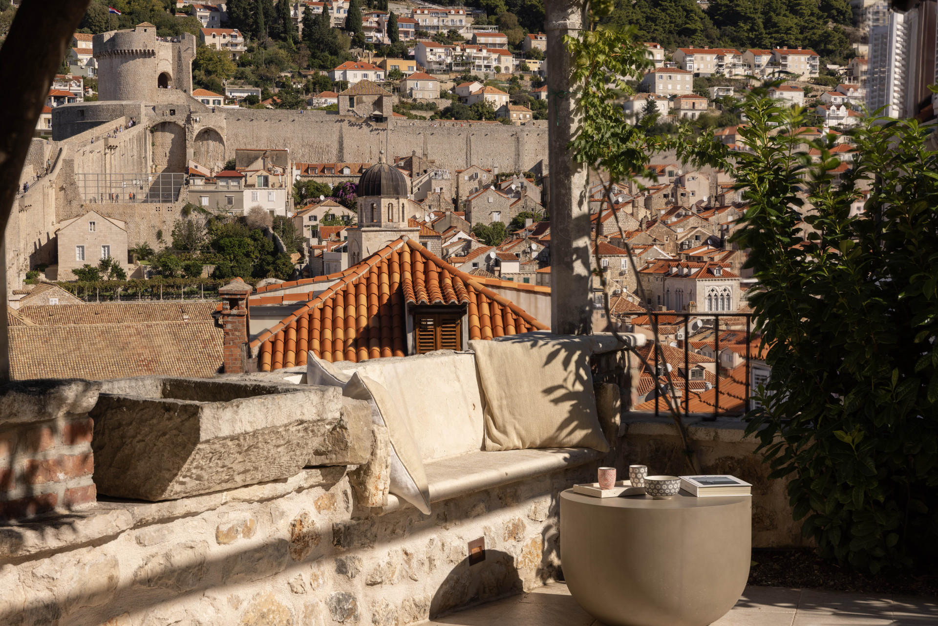 Charming stone terrace at Villa Nerolika with a cozy seating area overlooking Dubrovnik’s historic Old Town, red-tiled rooftops and ancient city walls.