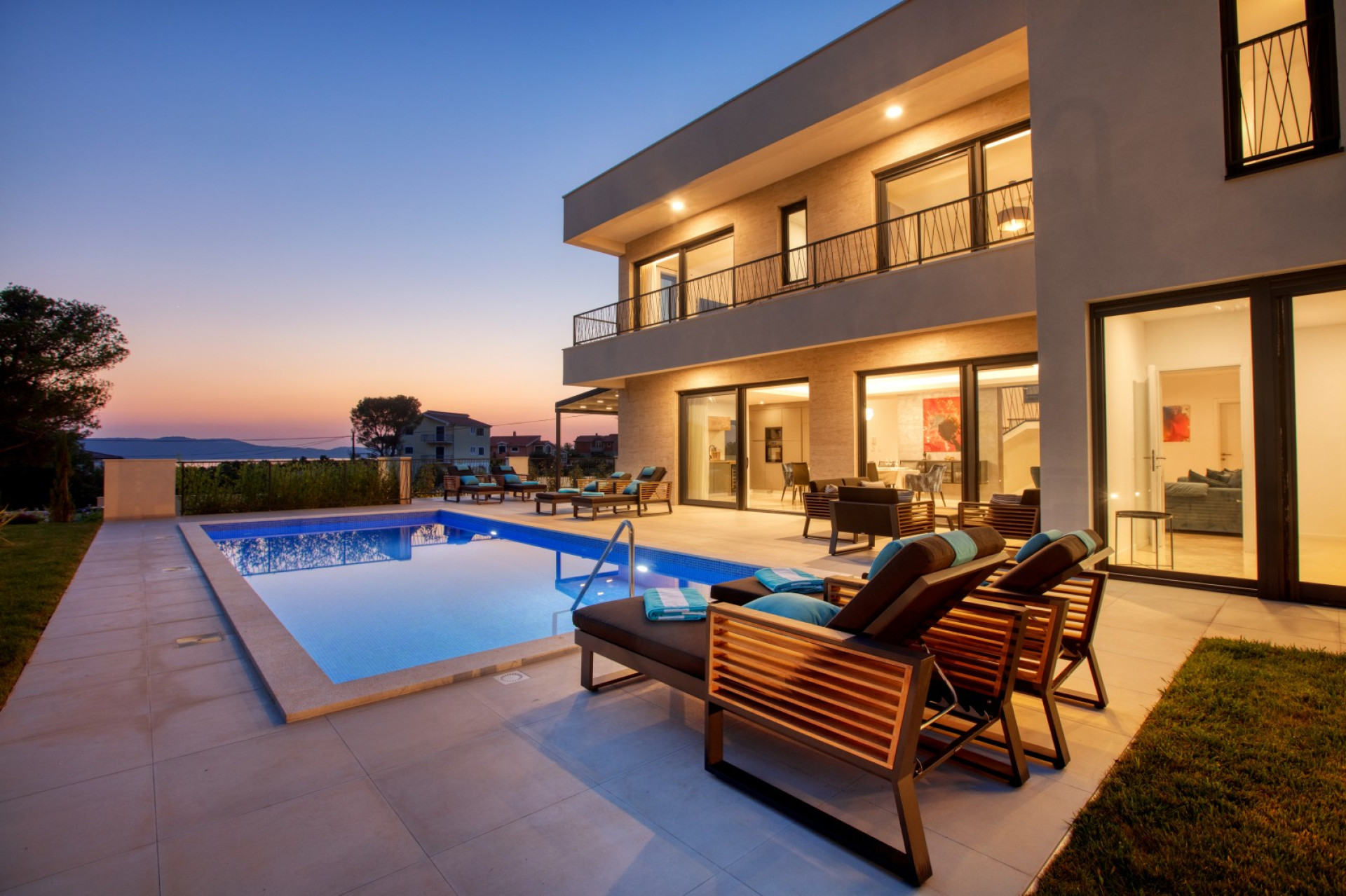 Luxury Villa Spuga near Šibenik with illuminated private pool, sun loungers and sea view at sunset.