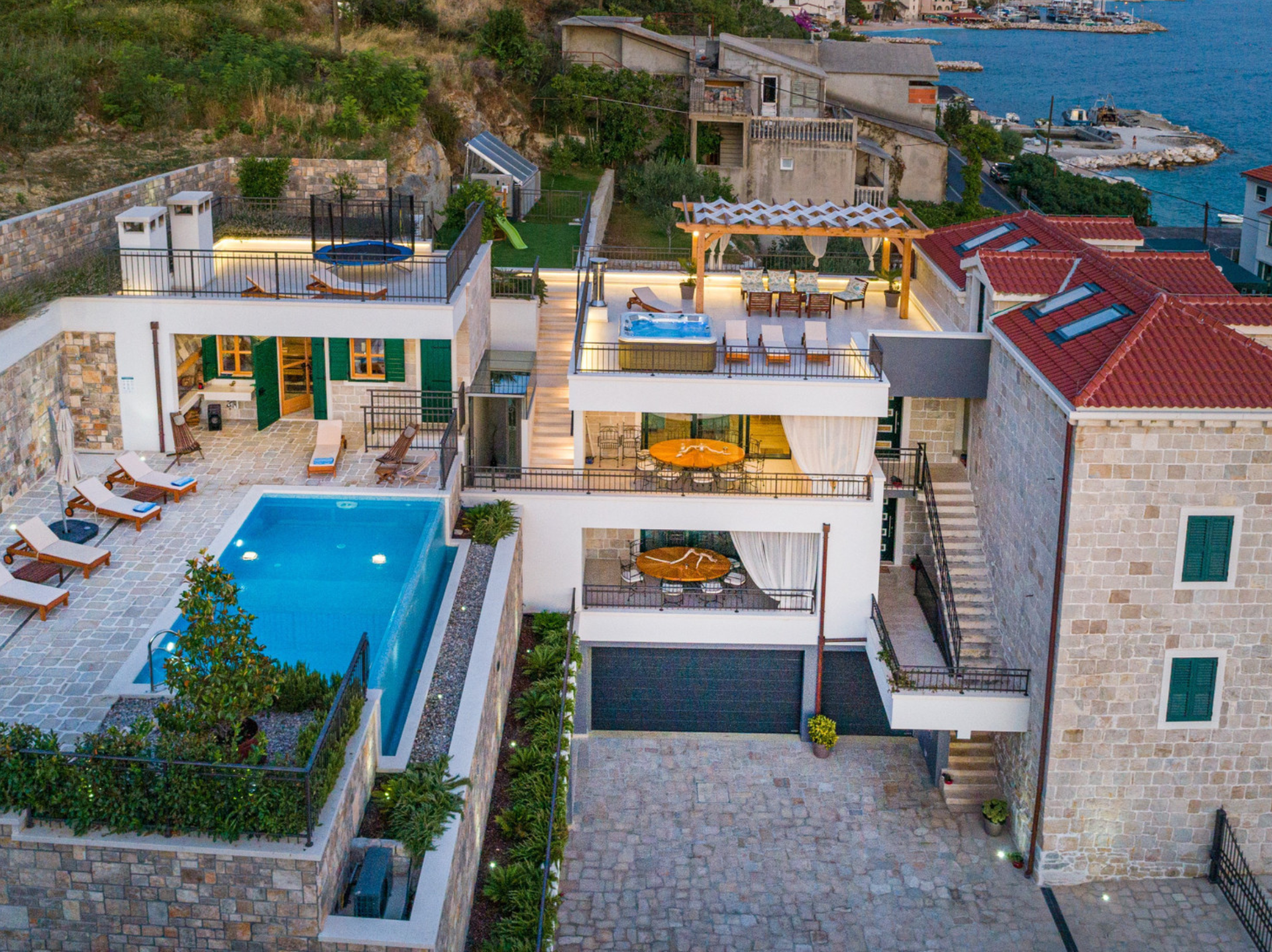 Aerial view of Villa Mladenka, a luxury stone villa with a private swimming pool, rooftop terrace with jacuzzi, and sea views on the Croatian coast.