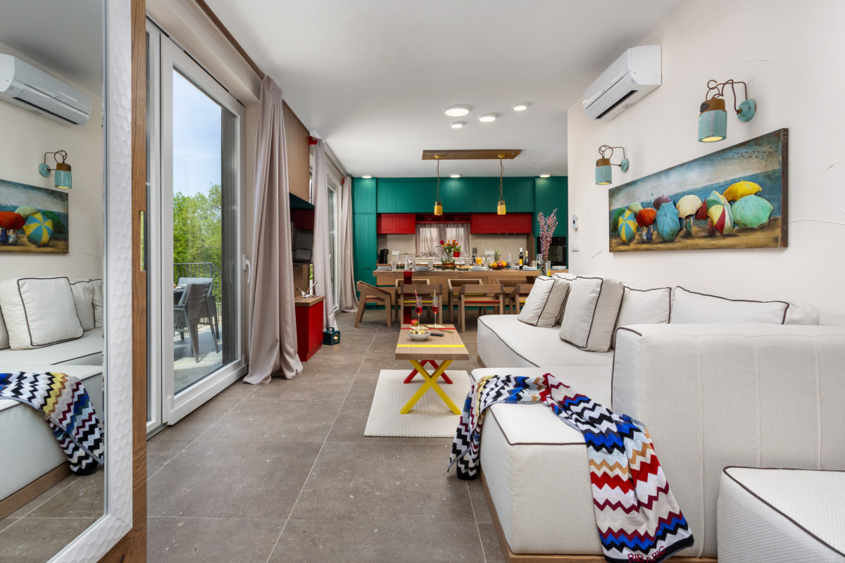 Vivaci interni open-plan di Villa Signature Krk, con una moderna cucina colorata, un'elegante zona lounge e grandi porte a vetri.