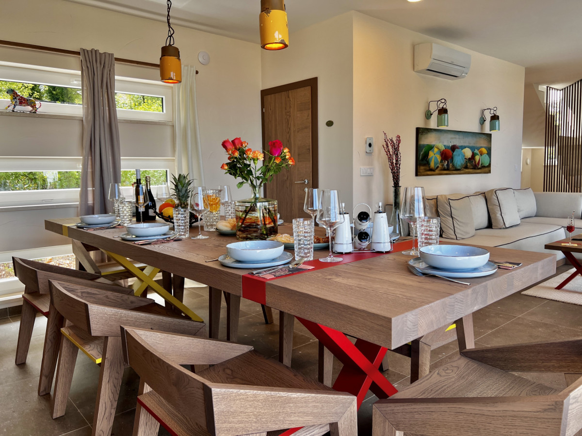 Ampia zona giorno e pranzo open-plan a Villa Signature Krk, con un grande tavolo in legno per 8 persone e arredi moderni ed eleganti.