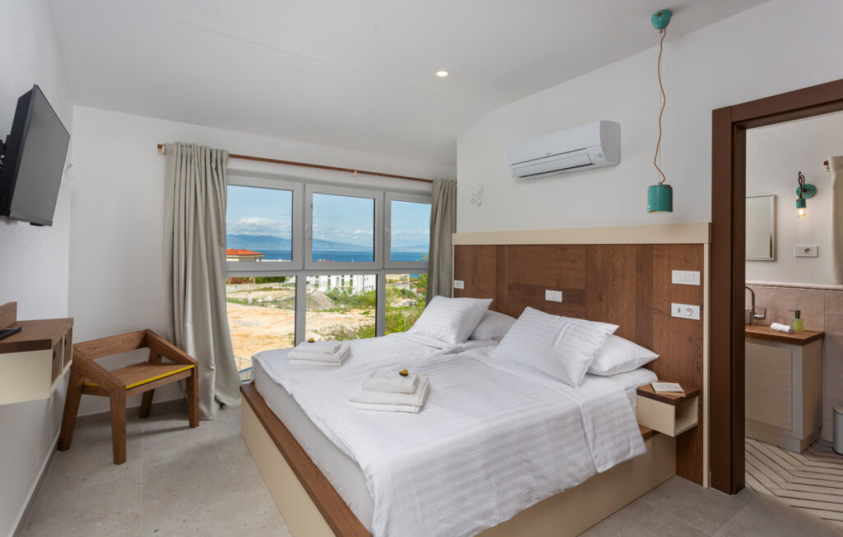Moderna camera da letto en-suite presso Villa Signature Krk, con un comodo letto matrimoniale con vista mare.