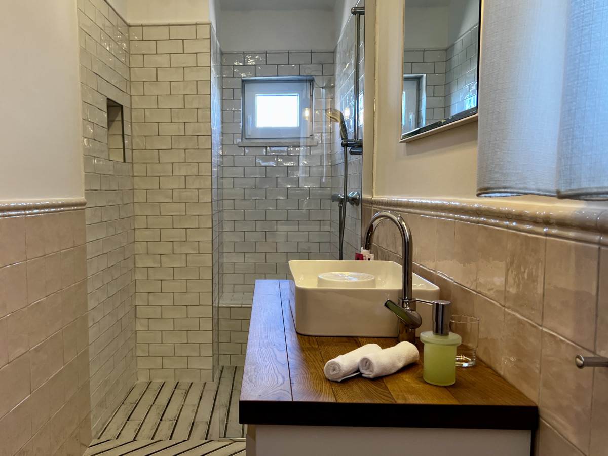 Moderno bagno privato presso Villa Signature Krk, con un'elegante doccia walk-in e un mobile lavabo in legno.