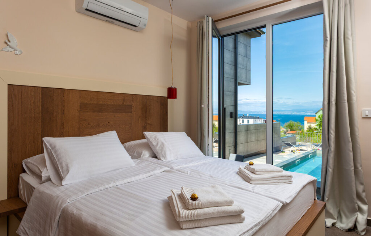 Moderna camera da letto en-suite presso Villa Signature Krk con vista piscina e mare, letto matrimoniale e accesso diretto al balcone.