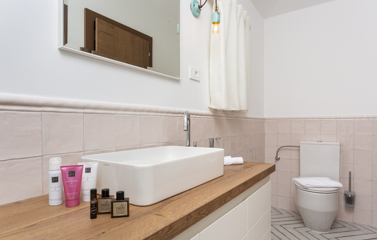 Set di cortesia di lusso presso Villa Signature Krk, con un moderno lavabo da appoggio su un mobile in legno e prodotti da bagno premium.