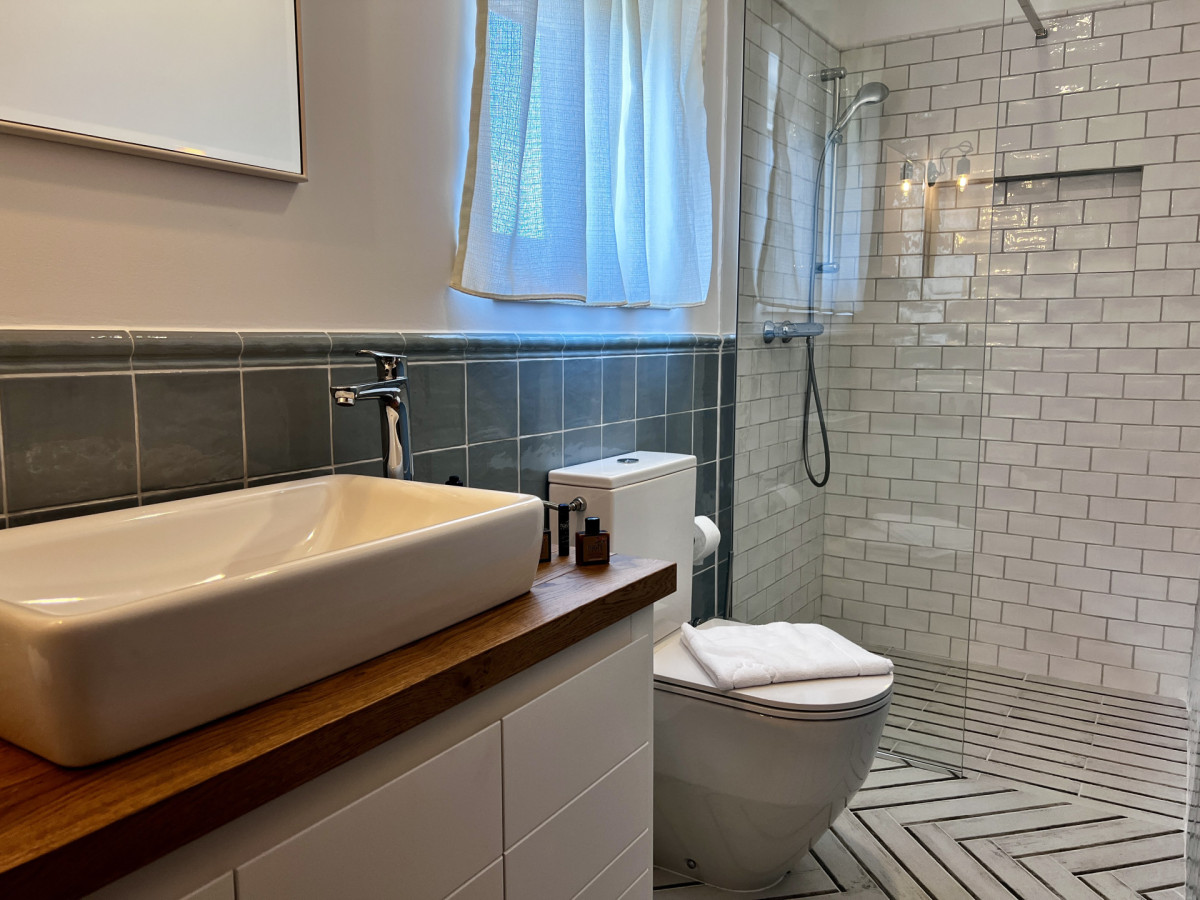 Elegante bagno moderno presso Villa Signature Krk, con un'ampia doccia walk-in con piastrelle diamantate e un moderno mobile lavabo in legno.