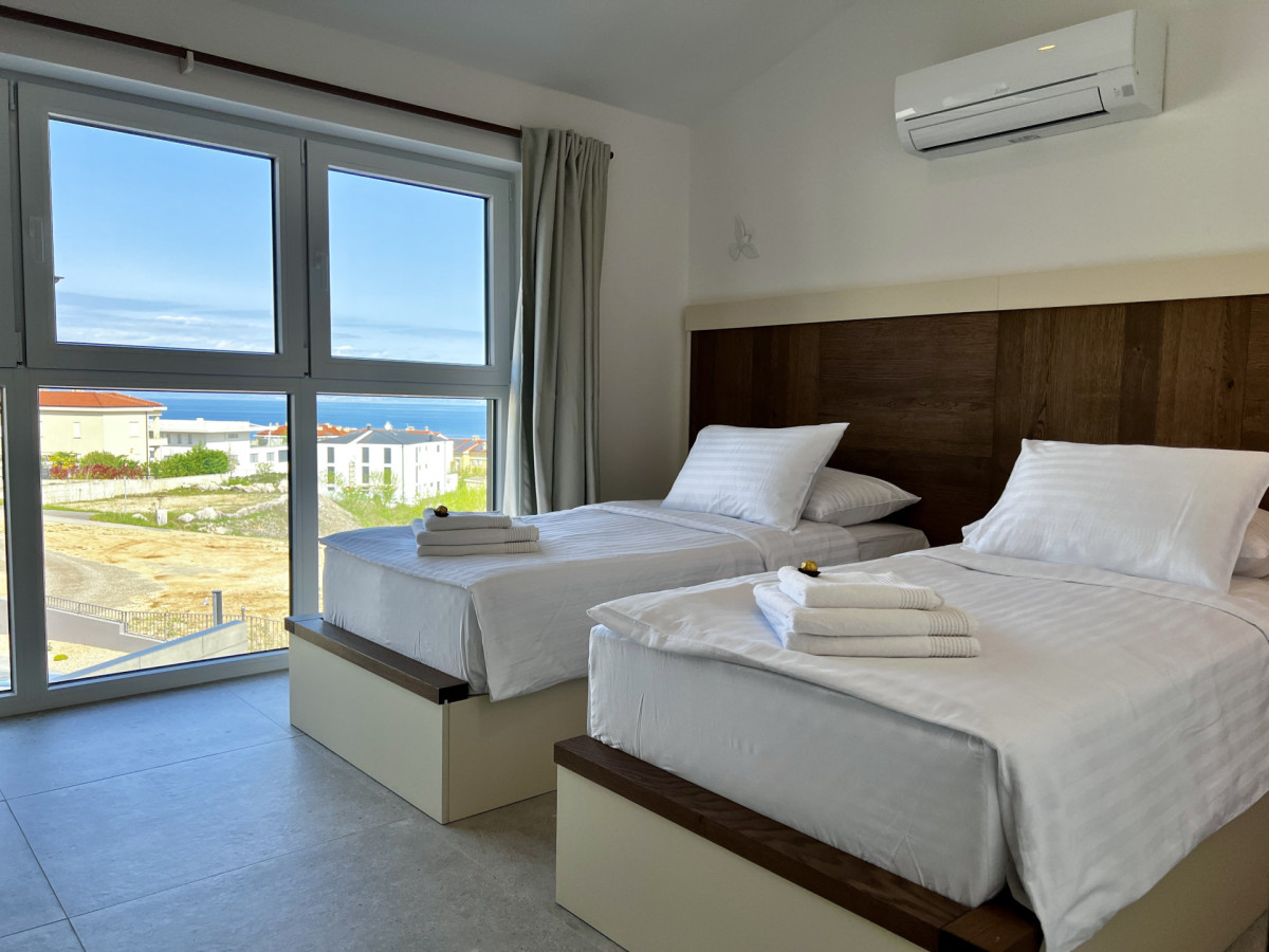 Moderna camera da letto doppia en-suite presso Villa Signature Krk, con vista mare attraverso ampie finestre e un design pulito.
