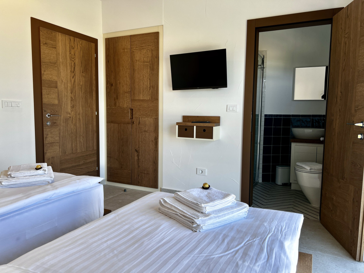 Moderna camera da letto doppia en-suite presso Villa Signature Krk, con TV a muro, armadi in legno a incasso e bagno privato.