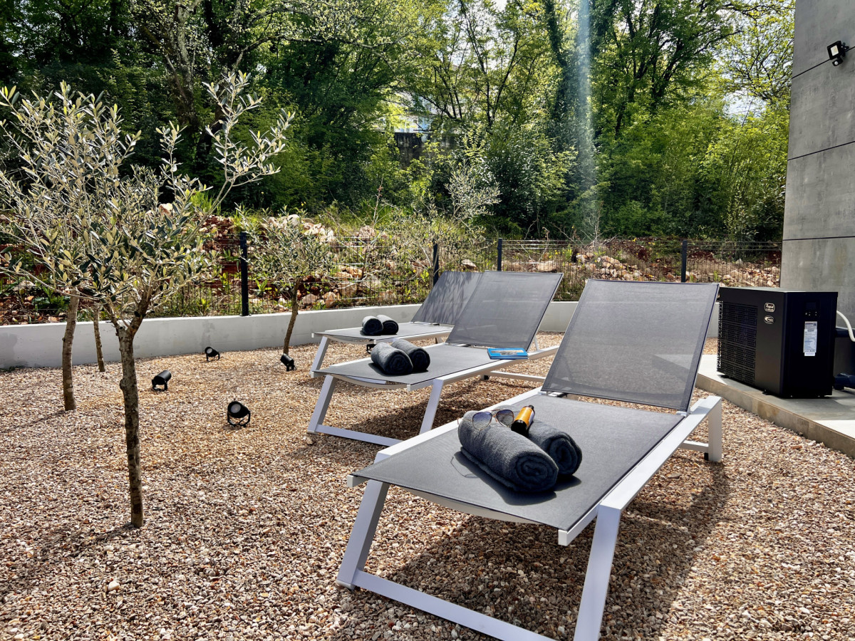 Angolo di relax privato presso Villa Signature Krk, con moderni lettini su ghiaia tra giovani ulivi e verde naturale.