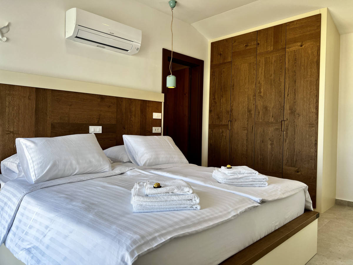 Moderna camera da letto en-suite presso Villa Signature Krk, con un grande letto matrimoniale, aria condizionata ed eleganti armadi in legno a tutta altezza.