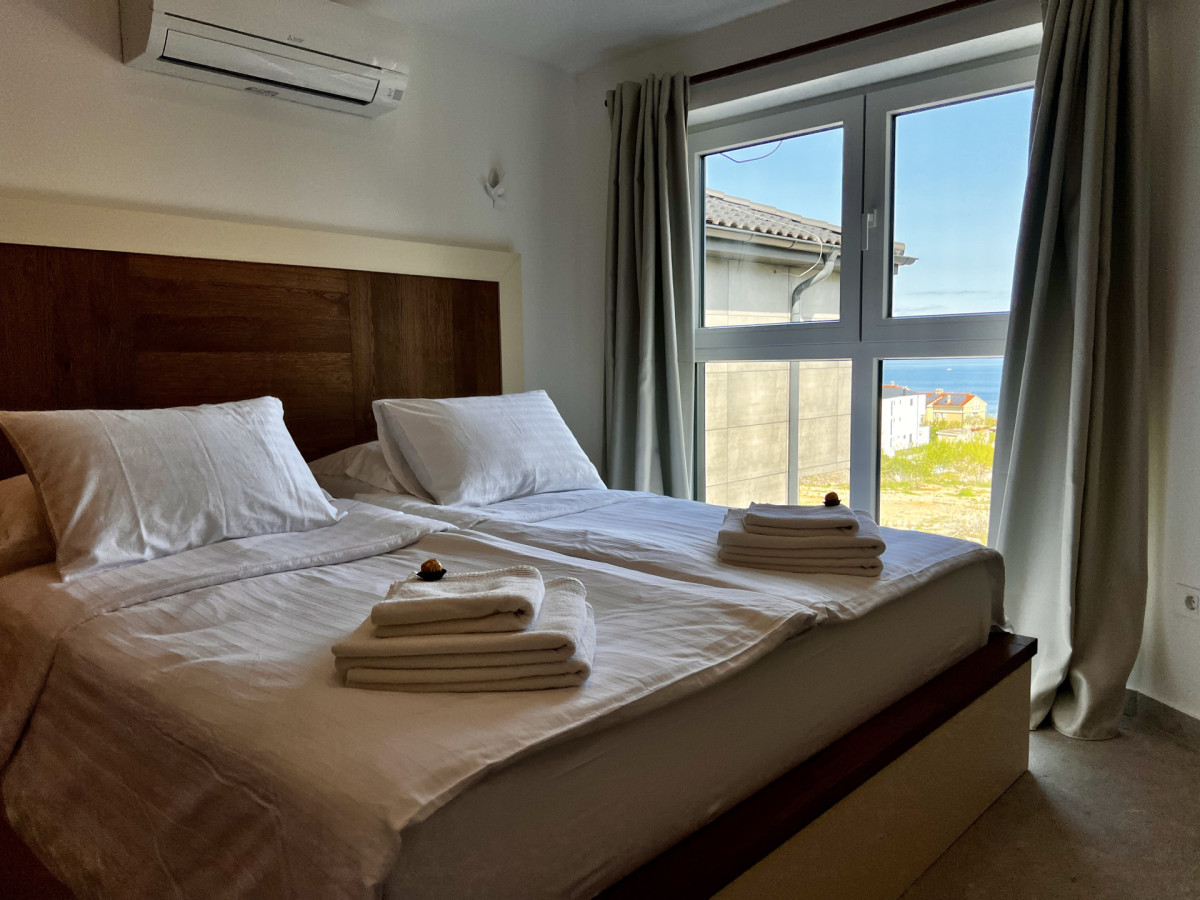 Moderna camera da letto presso Villa Signature Krk con finestre a tutta altezza e vista mare, dotata di un grande letto matrimoniale e aria condizionata.