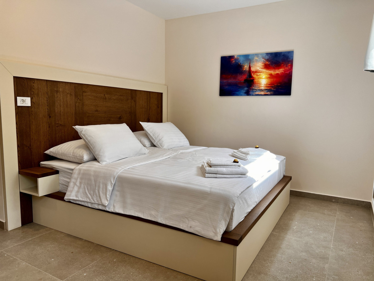 Accogliente camera da letto moderna presso Villa Signature Krk, con un letto matrimoniale con fresche lenzuola bianche e decorazioni murali a tema nautico.