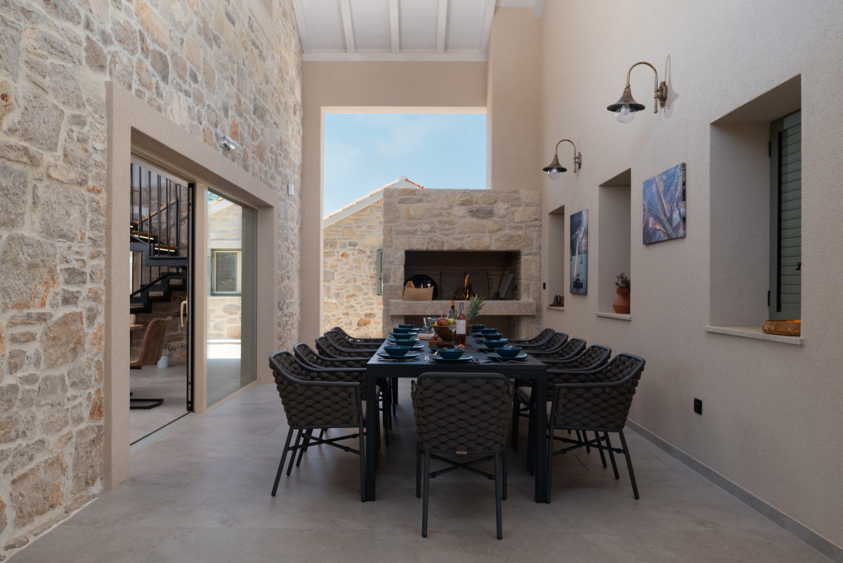 Elegant Covered Patio with Woven Chairs, Outdoor Grill and High Ceilings
