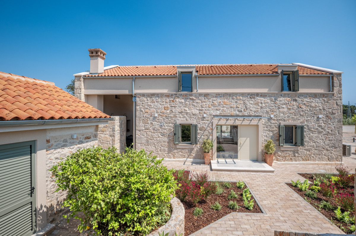Villa Utopia on Ugljan, a majestic stone residence with a lush garden, paved courtyard, and inviting entrance.