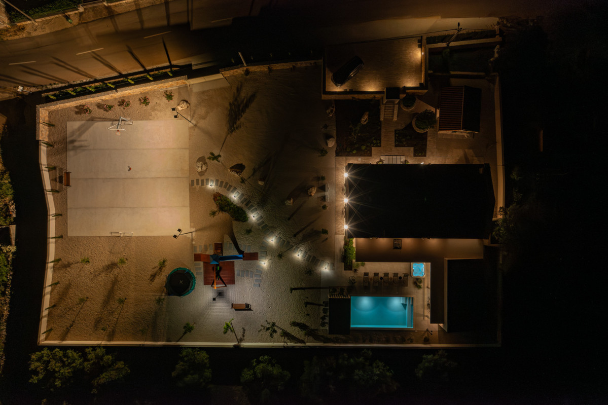 Aerial night view of Villa Utopia’s illuminated courts and pool