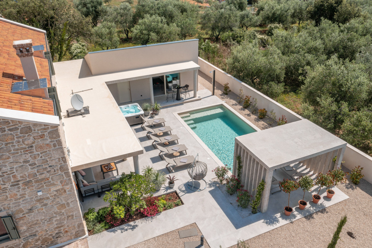 Aerial perspective of Villa Utopia featuring a traditional stone structure, modern sundeck with pool and jacuzzi, and a covered lounge area overlooking Ugljan’s lush olive trees.