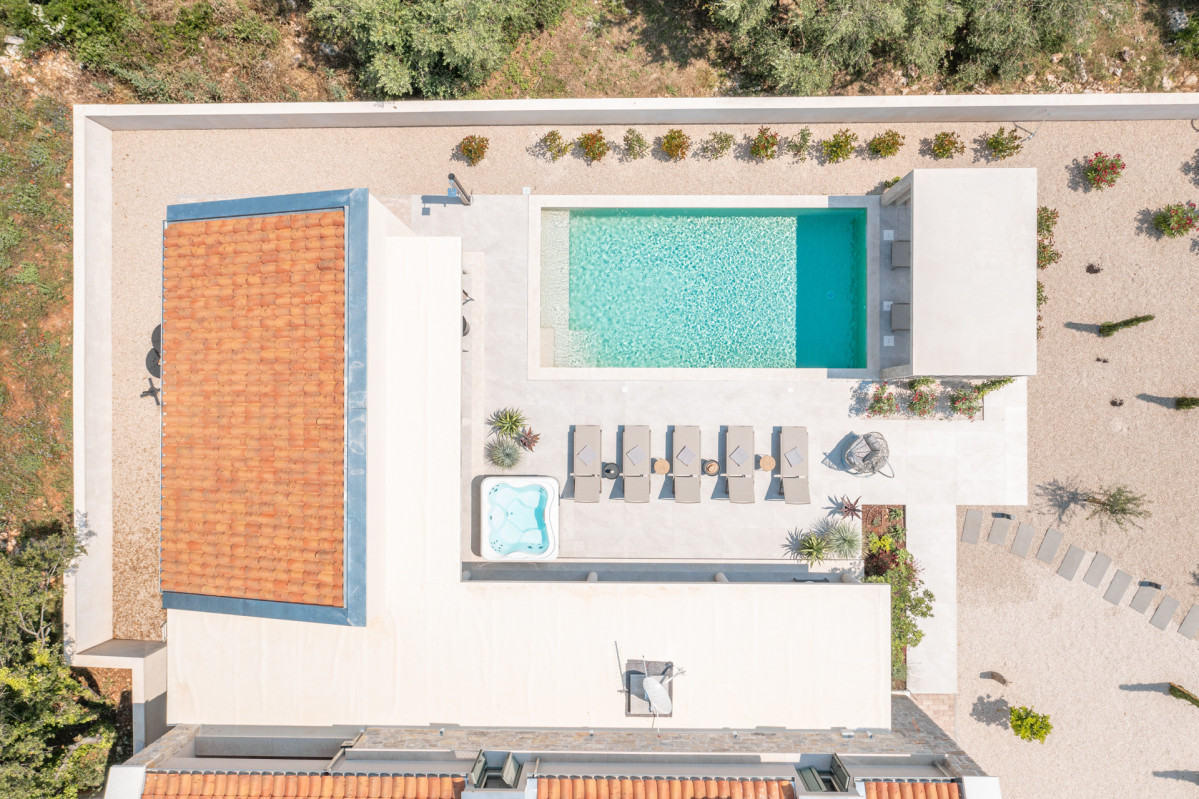 The private, tranquil courtyard of Villa Utopia, featuring a crystal-clear pool, sleek sun loungers, and warm terracotta architecture.