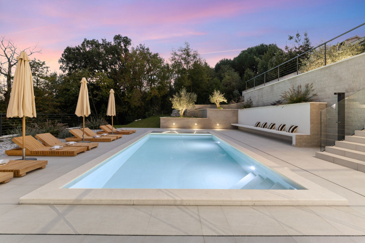 Beleuchteter privater Pool der Villa Casa Calme in der Dämmerung, mit hölzernen Sonnenliegen und einem modernen, steingepflasterten Loungebereich.