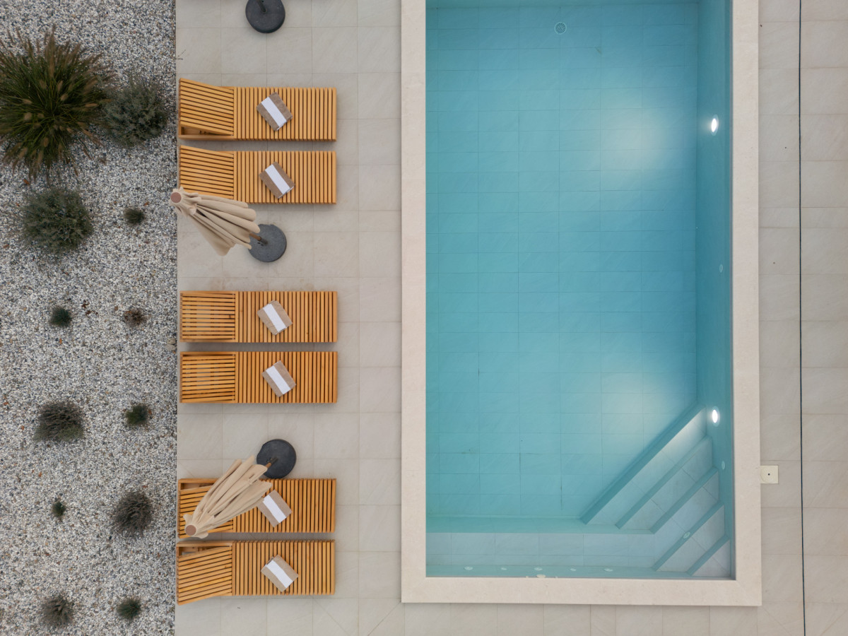 Türkiser Pool und hölzerne Sonnenliegen mit Handtüchern in der Villa Casa Calme