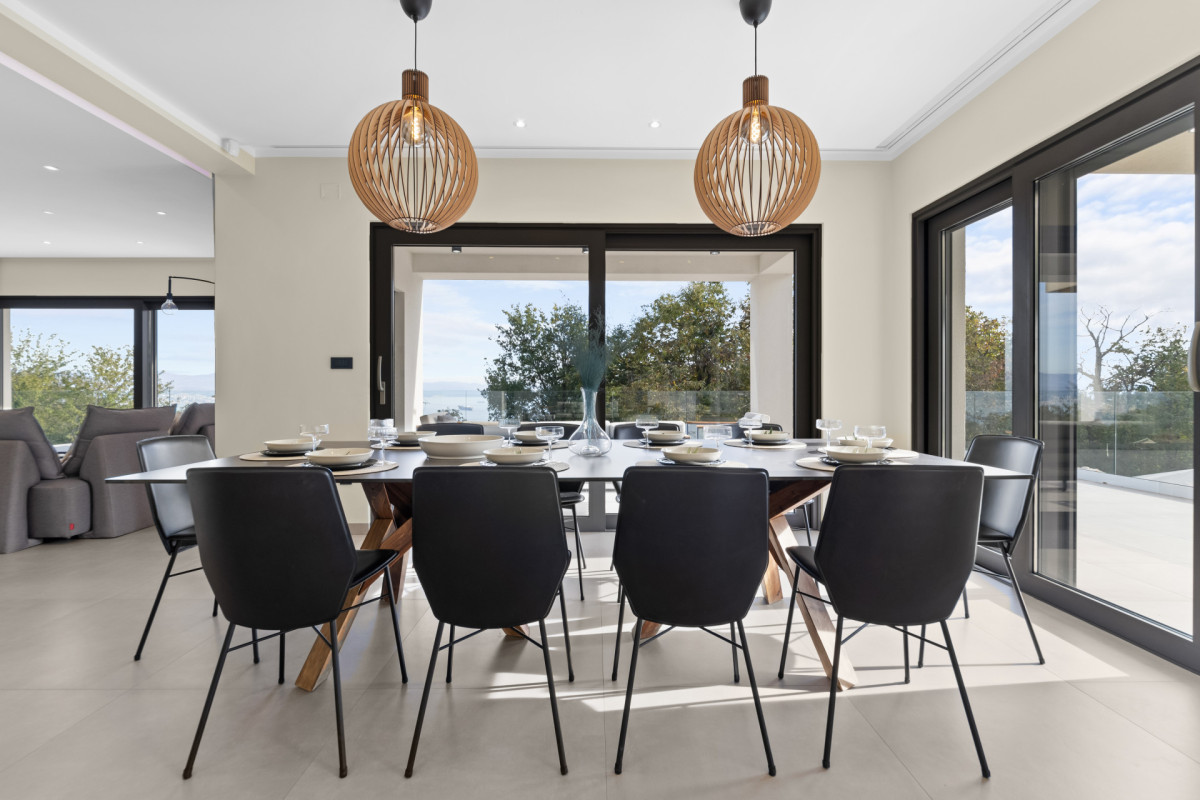 Eleganter offener Essbereich in der Villa Casa Calme: zeitgenössische Möbel und raumhohe Glastüren, die zur Terrasse führen – perfekt für gemeinsame Abendessen in der Gruppe.