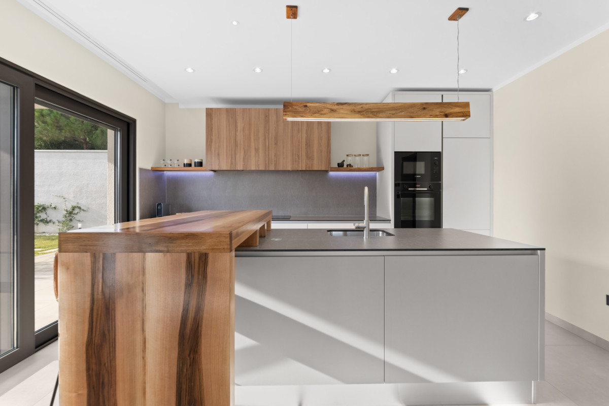 Zeitgenössisches Kücheninterieur mit hochwertigen Bosch-Geräten, minimalistischen grauen Schränken und einer warmen Holz-Arbeitsplatte – eine perfekte Verbindung von Luxus und Funktionalität.