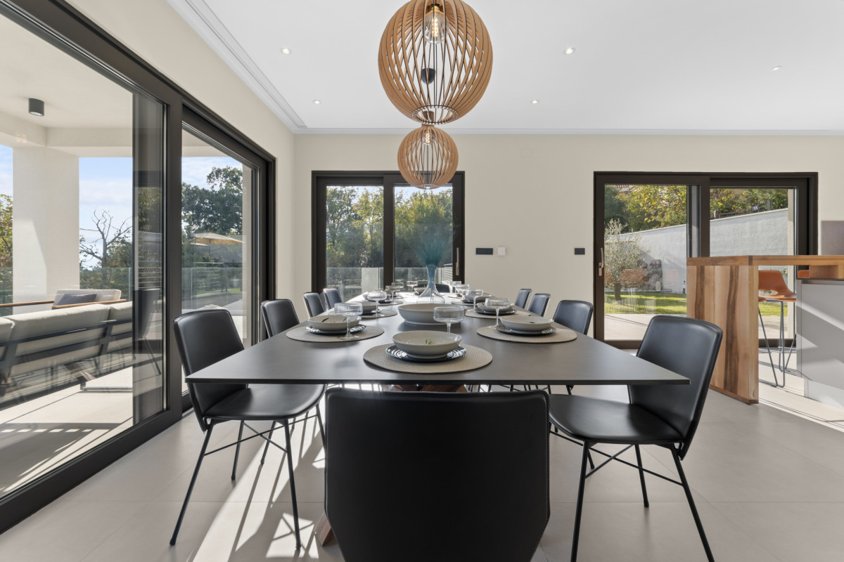 Zeitgenössischer Essbereich in der Villa Casa Calme mit minimalistischen schwarzen Stühlen, Designer-Kugelleuchten und einer Fülle an natürlichem Licht.