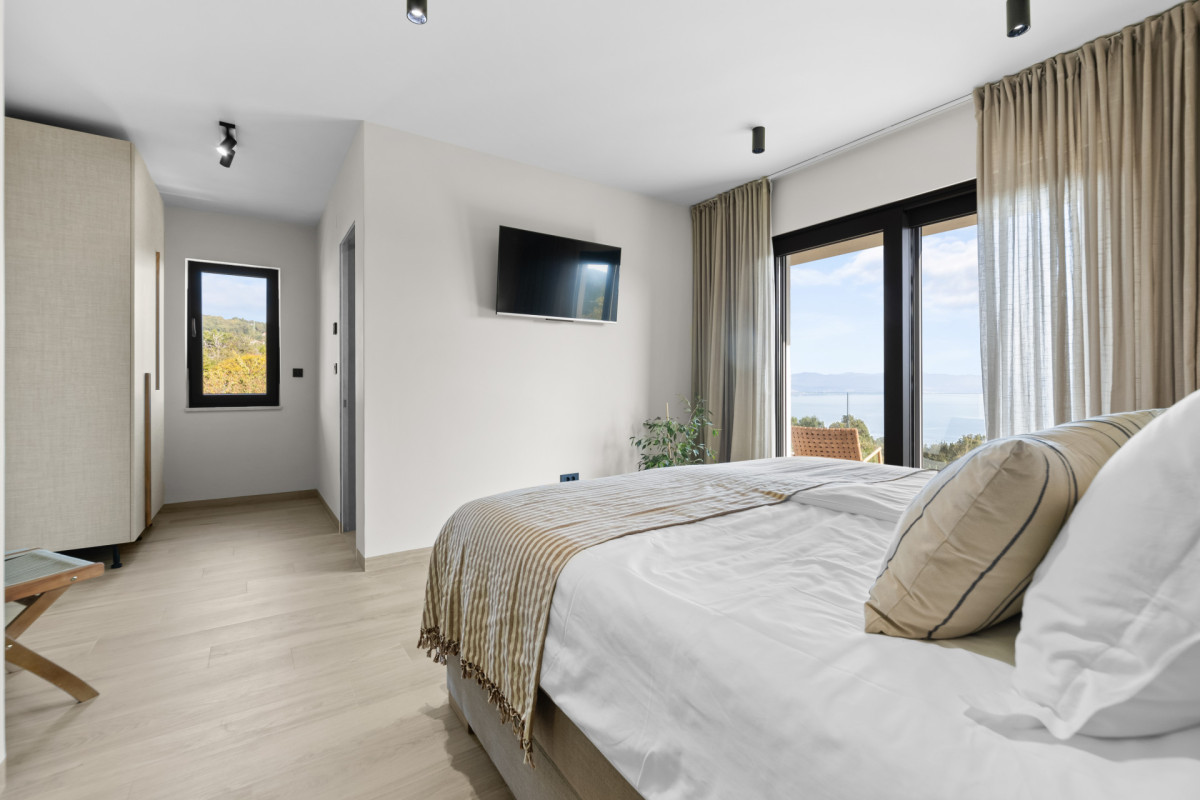 Helles und luftiges Schlafzimmer mit eigenem Bad in der Villa Casa Calme: minimalistisches Dekor, neutrale Töne und raumhohe Fenster mit Blick auf die Adriaküste.