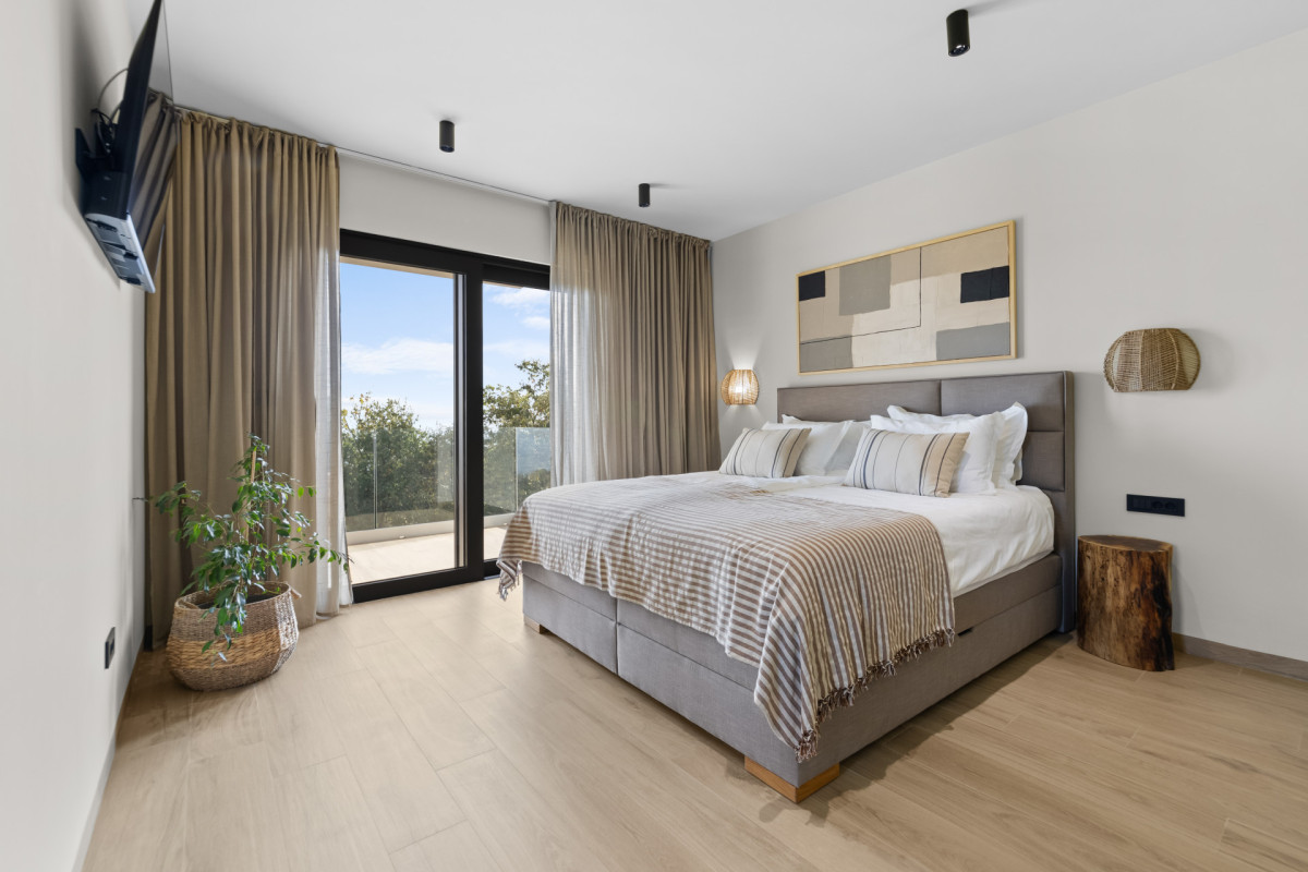 Eleganzes Schlafzimmer mit eigenem Bad in der Villa Casa Calme: mit einem großen gepolsterten Bett, moderner Kunst und direktem Zugang zu einem privaten Balkon mit Meerblick.