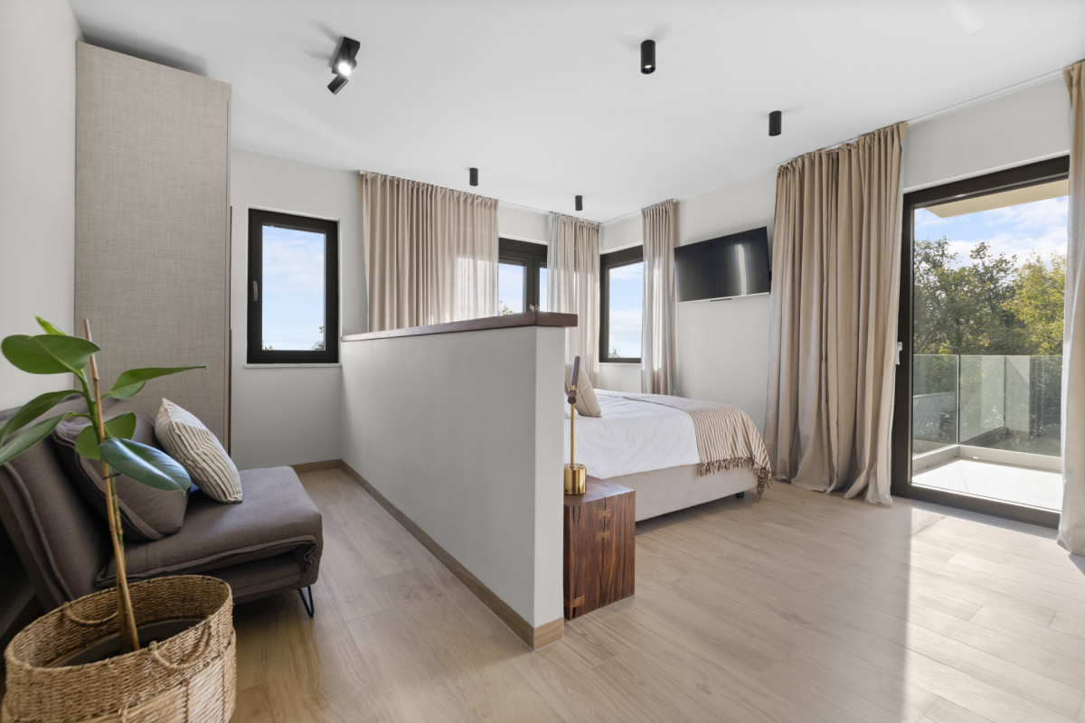 Vielseitiges Schlafzimmer mit eigenem Bad in der Villa Casa Calme: mit einem großen Bett, einem zusätzlichen Schlafsofa für weitere Gäste und einem privaten Balkon mit Blick in die Natur.