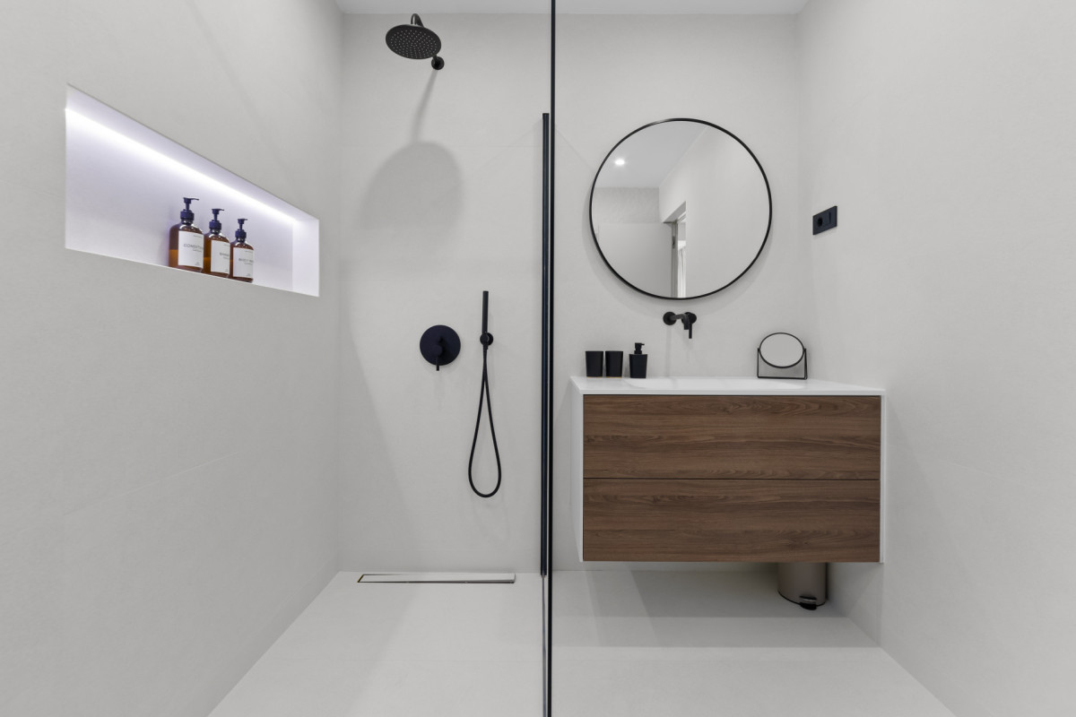 Ultramodernes En-Suite-Badezimmer in der Villa Casa Calme mit einer minimalistischen begehbaren Dusche, eleganten schwarzen Armaturen, einem schwebenden Waschtisch aus Holz und einer beleuchteten Wandnische.