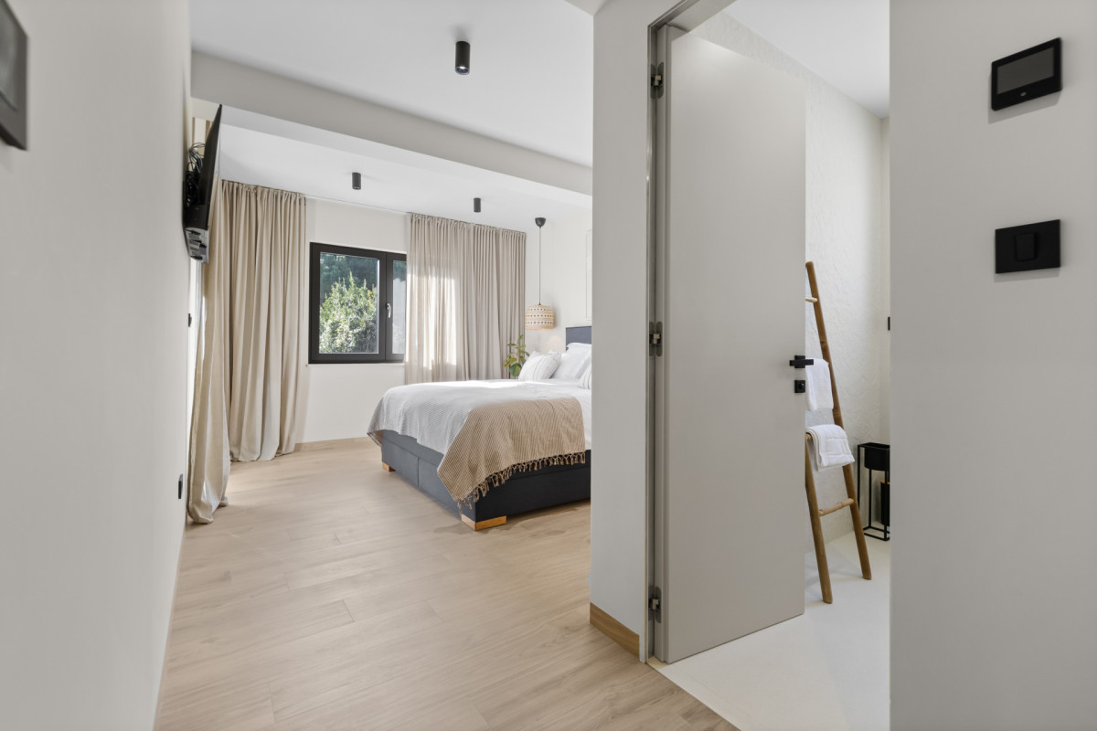 Blick in den Eingangsbereich eines luxuriösen Schlafzimmers mit eigenem Bad in der Villa Casa Calme, der den fließenden Übergang zwischen dem modernen Schlafbereich und dem privaten Badezimmer zeigt.