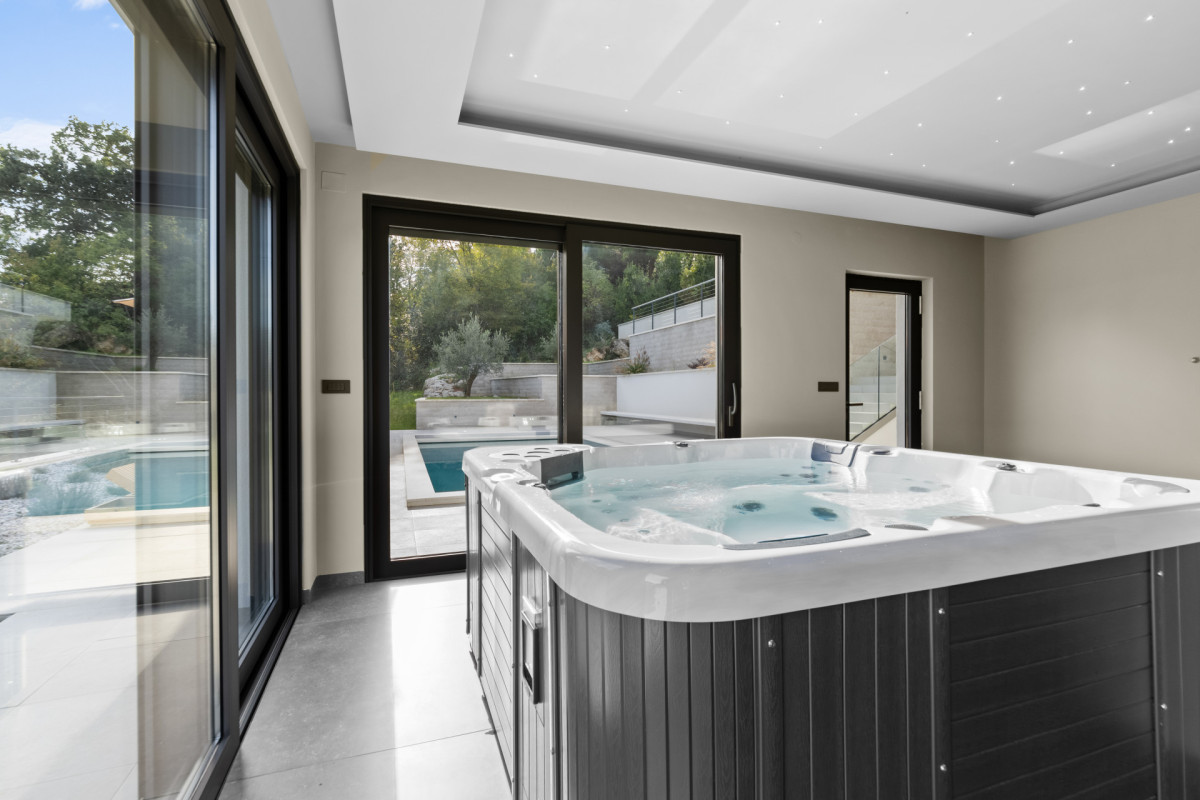 Erholsame private Wellness-Zone in der Villa Casa Calme: ein moderner Indoor-Whirlpool und eine Deckenbeleuchtung im Sternenhimmel-Design, mit nahtlosem Übergang zur Außenpool-Terrasse.
