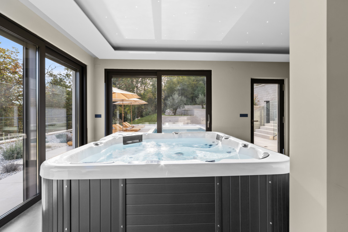 Moderner privater Wellnessbereich mit einem High-End-Whirlpool unter einem Sternenhimmel, ergänzt durch große Glasschiebetüren, die direkt zum Sonnenbereich der Villa Casa Calme führen.